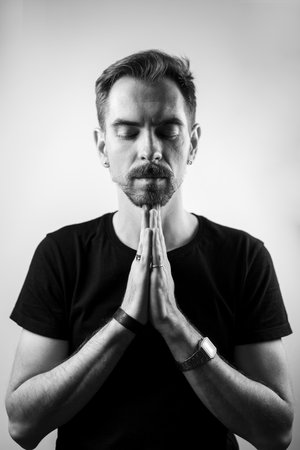 Peaceful calm man with closed eyes and hands together over the chest. Black and whiteの写真素材