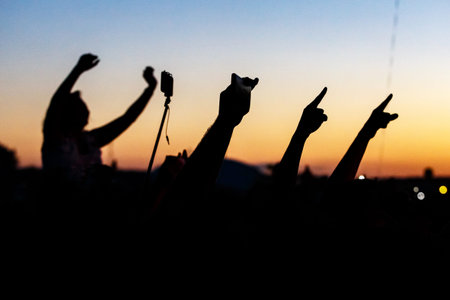 Raised hands of many people at a big mass event.
