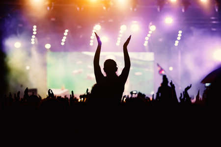 Raised hands in honor of a musical show on stage, People in the hallの写真素材