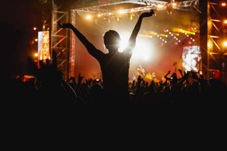 Silhouette of girl with raised hands on music concert.の写真素材