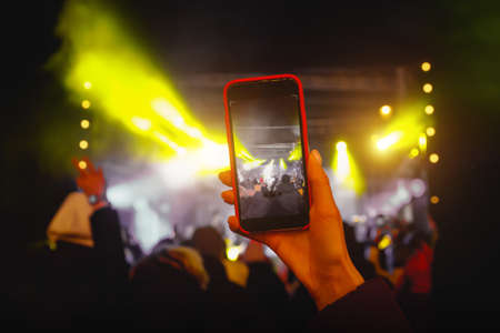 Recording a concert with mobile phone, silhouette of hands with smartphone.の写真素材