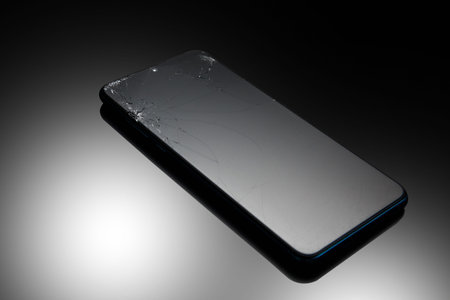 Mobile phone with a broken screen on a black background