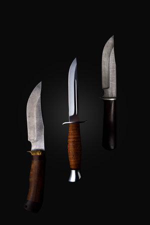 Set of knifes made of Damascus steel with a wooden handle on a isolated dark background.の写真素材