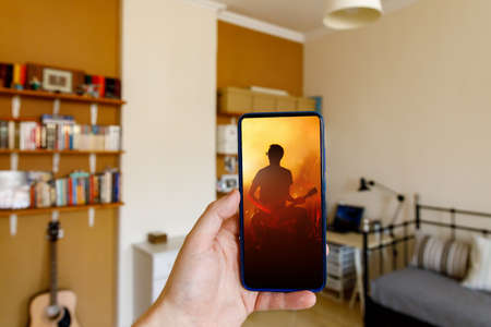 Watching online concert at home via mobile phoneの写真素材