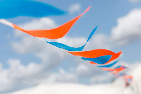 Small colorful orange and blue triangular flags against the sky background. Festival decorの写真素材