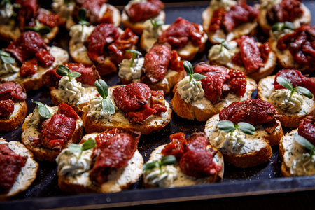Meat bruschetta on a black tray. Beef and dried tomato on a baguette.の写真素材