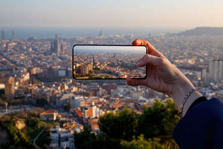 Travel concept - tourist taking a photo of Barcelona skyline on a mobile phone, Spainの写真素材
