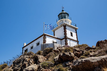 Old lighthouse with Greece flag on blue sky backgroundの写真素材