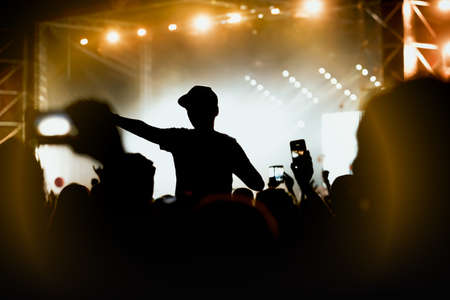 Viewers under the stage. The man with raised hands during summer festival rock concertの写真素材