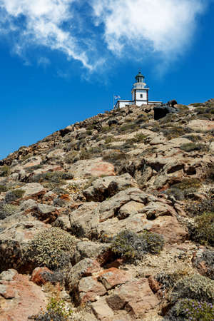 The old lighthouse on the rocky sea coast. Blue sky with cloudsの写真素材