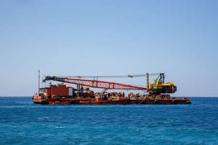 Construction barge with a crane in blue seaの写真素材