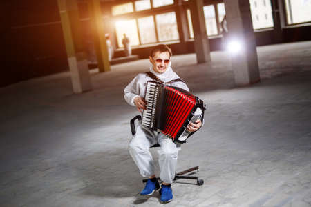 The musician playing the harmonica, accordion in the hall with columnsの写真素材