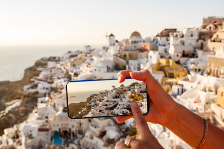 Photographing a landmark using a mobile phone camera. Famous view of Santorini in Greece on a...