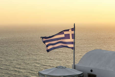Greek flag near Aegean sea during sunsetの写真素材