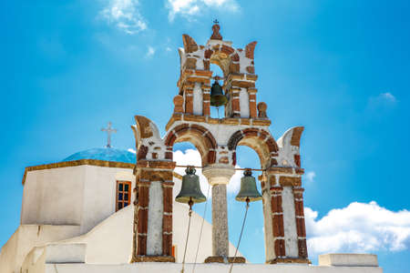 The bell tower on Santorini streets under blue sky during sunny dayの写真素材