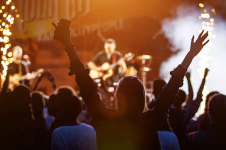 Happy crowd with raised hands at a rock concertの写真素材