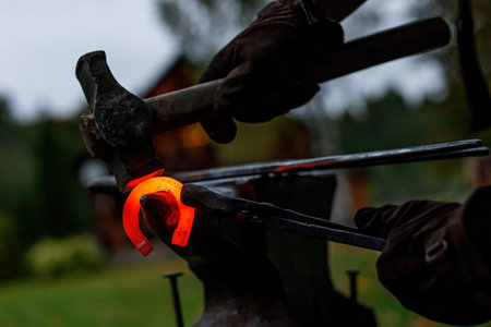 Horseshoe production process. A blacksmith bending hot metal on an anvilの写真素材