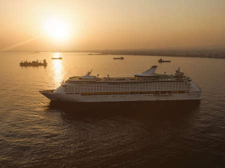 The luxury cruise liner in a port near big sea city during sunsetの写真素材
