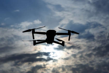 Black silhouette of a foldable drone flying in the skyの写真素材