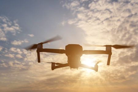 Black silhouette of a foldable drone flying in the sky