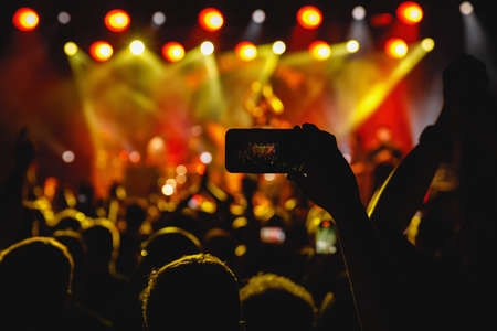 Holding a smartphone to record music concert. Mobile phone at a summer festivalの写真素材