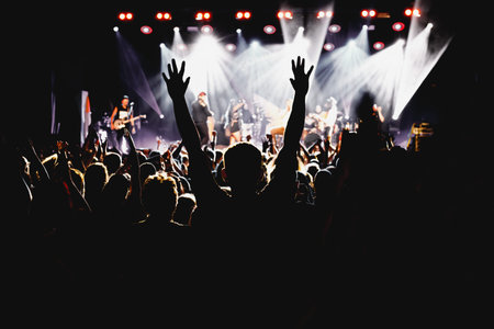 A crowd of happy people raising up hands at an open-air rock concertの写真素材