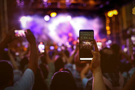 People holding their smartphones at concert and taking picturesの写真素材