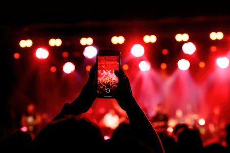 Holding a smartphone to record music concert. Mobile phone at a summer festival
