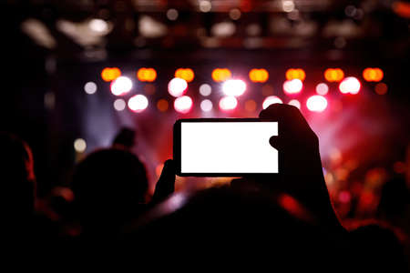 Smartphone in a hands on a music concert show, Blank white screen mockupの写真素材
