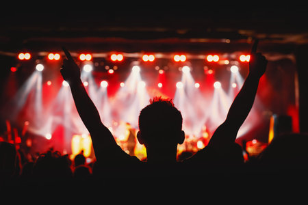 The man with raised hands during the music concert. Crowd and stage light in a concert hallの写真素材
