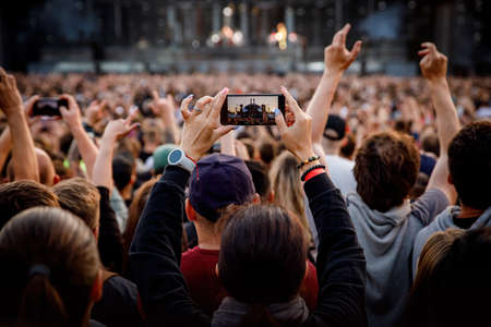 Smartphone in the hand of a music fan at the summer concert.の写真素材