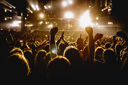 Silhouette of a happy crowd with hands up during a big rock concert