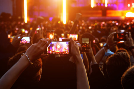 People with mobile phones record a music concert
