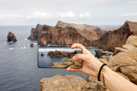 Taking photos of the cliff coastline. Using mobile phone in travel.