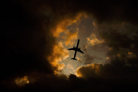 Airplane flies through orange dramatic clouds.の写真素材