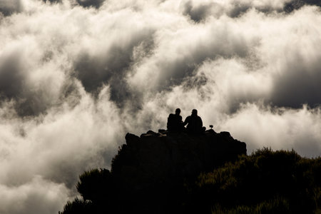 Two people on top of a mountain above the clouds.の写真素材