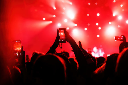 People at concert shooting video or photo using mobile phonesの写真素材