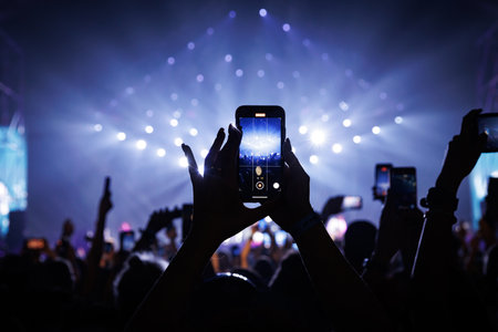 People at concert shooting video or photo using mobile phonesの写真素材