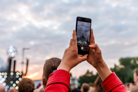 Smartphone in a Fan's Hand During an Outdoor Music Festival.の写真素材