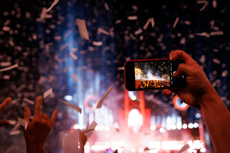 Crowd of people having fun while watching confetti fireworks at music festivalの写真素材