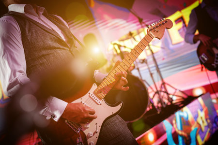 A close-up shot of a guitarist playing their guitar live on stageの写真素材