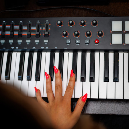 Woman with red nails playing electronic musical keyboard synthesizerの写真素材
