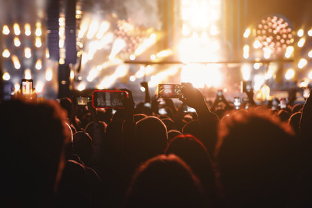 Performance of a popular group. The crowd with raised hands against the stage light.の写真素材