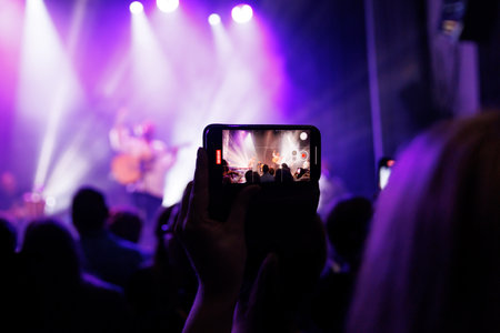 Large group enjoying a bright, illuminated rock concert with stage lights.の写真素材