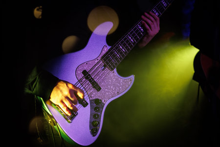 Bass guitarist playing live concert with rock band.