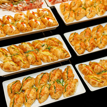 A lavish spread of gourmet appetizers, featuring golden croissants garnished with fresh herbs and a...