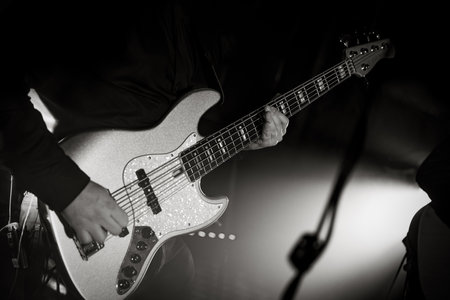 Close-up of a bass guitar during a concert performance. Black and white Guitarist bass on stage