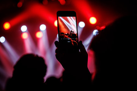Making photo with smartphone during a concert to share the moment with friends on social networksの写真素材