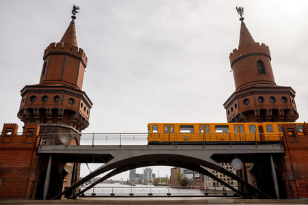 Yellow Berlin metro cars moving along the red brick historic bridge
