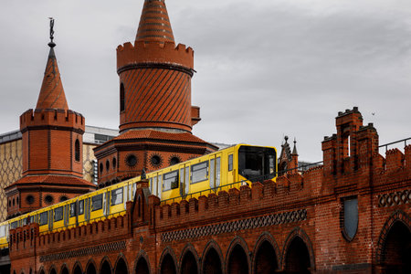 Yellow Berlin metro cars moving along the red brick historic bridgeの写真素材